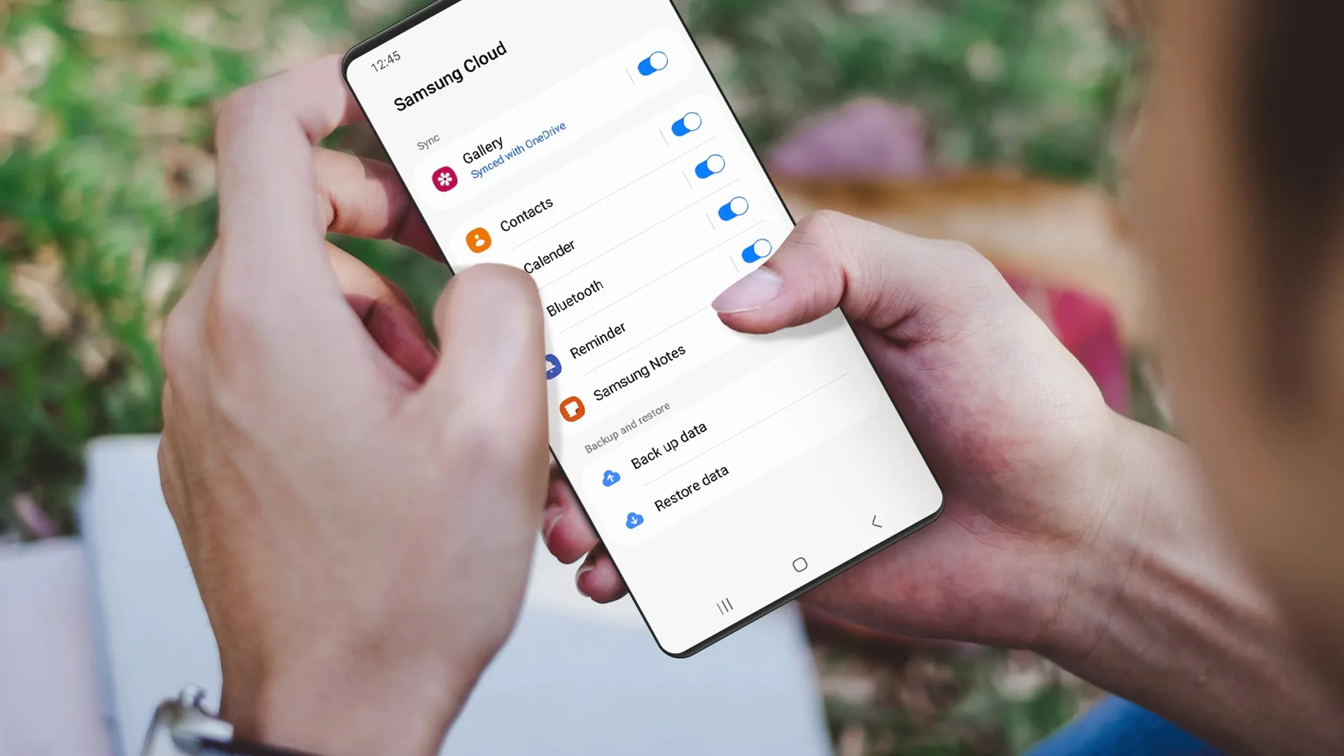 Una mujer sosteniendo un teléfono celular samsung galaxy, abriéndo la configuración de Samsung Cloud